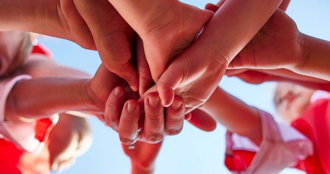 Niños uniendo manos en equipo